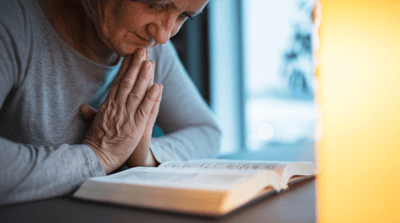 A woman praying while reading a book in a serene environment