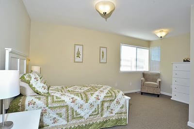 Well-lit bedroom with floral bedding and armchair