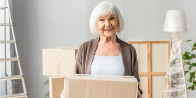 Smiling senior woman holding a box indoors.