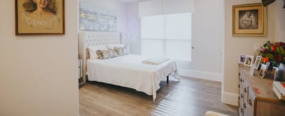 Bright, well-decorated resident room with a bed and artwork