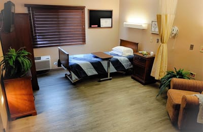 A comfortable resident room with a bed and chair