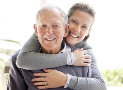 Smiling senior man with a woman embracing him