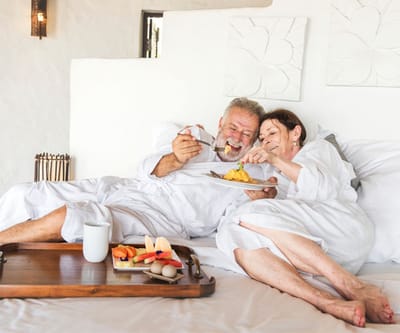 Couple enjoying breakfast in bed at a senior living facility