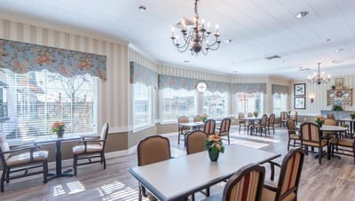 Bright dining room with floral decor and tables set for residents