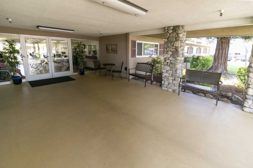 Covered outdoor sitting area with benches and plants