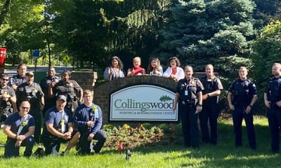 Staff and community members posing outside the facility sign