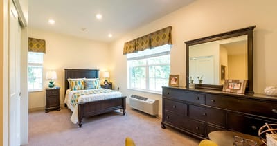 A comfortable resident room with a bed and dresser
