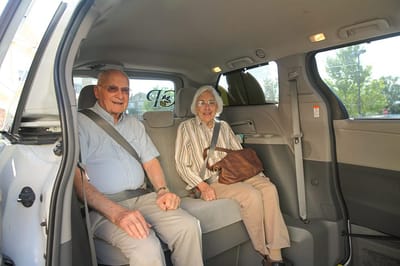 Two seniors happily seated in a vehicle