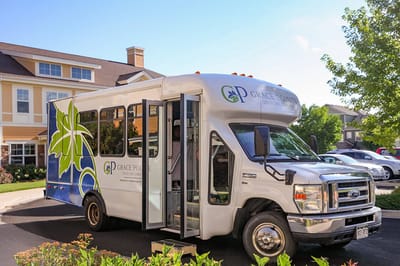Facility transport bus with branding in front of the building