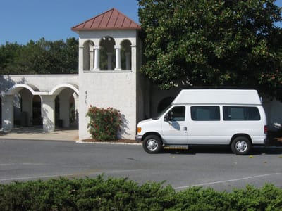 Exterior view of Harrison House with facility transport van