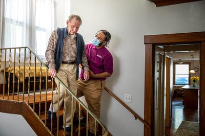 A staff member assisting a resident on the stairs