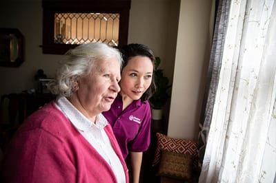 Senior woman and caregiver looking out a window