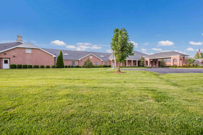 Exterior view of a senior living facility with green lawn