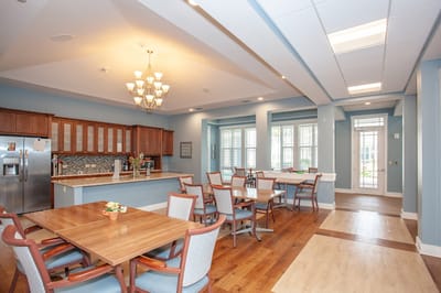 Bright dining area with tables and kitchen in a senior living facility