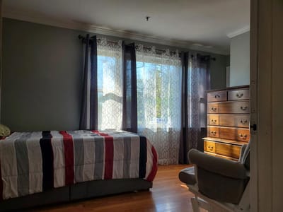 Brightly lit resident room with a bed and dresser