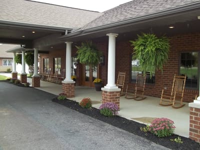 Exterior view of a nursing home entrance with rocking chairs
