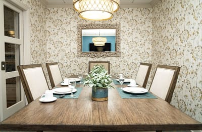 Dining room set for a meal with floral wallpaper