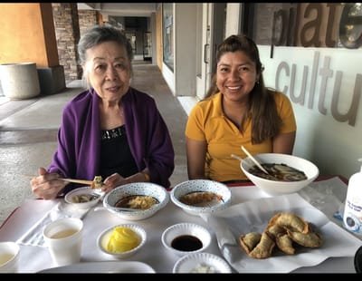 Senior resident enjoying a meal with staff member