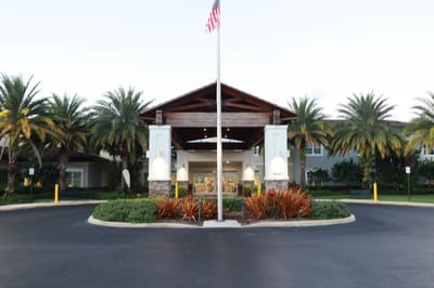 Entrance of the facility with palm trees and flag