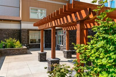 Outdoor patio area with wooden pergola and landscaping