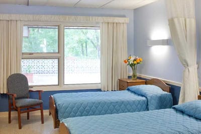 A shared resident room with two beds and a vase of flowers
