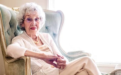 A senior woman sitting in a vintage chair