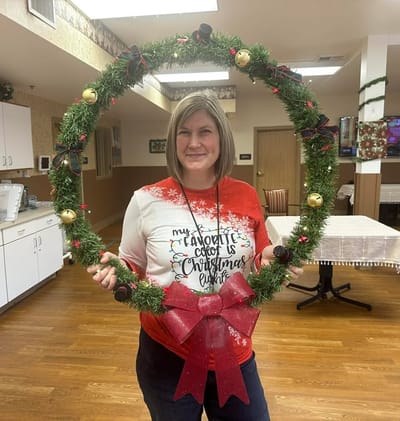 Staff member holding a festive holiday wreath