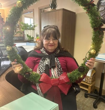 Staff member holding a festive wreath at the front desk