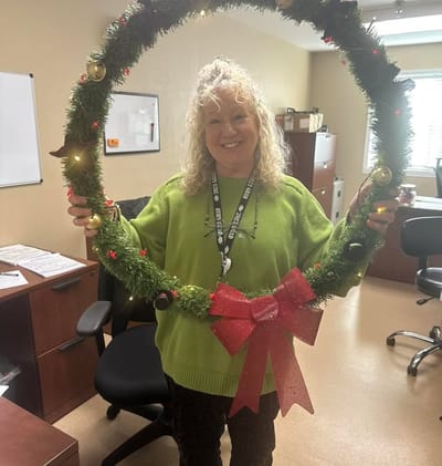 Staff member holding a Christmas wreath in the office