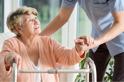 Caregiver assisting an elderly woman in a bright room