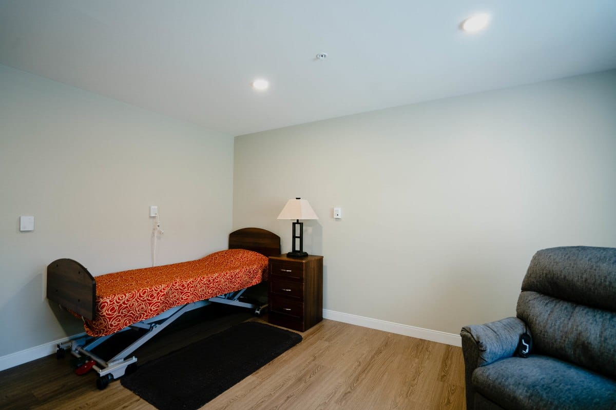 A private resident room with a bed and lamp