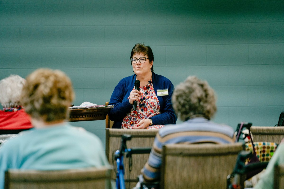 A staff member speaking to residents in an activity room