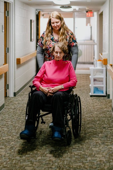 A staff member assisting a resident in a hallway