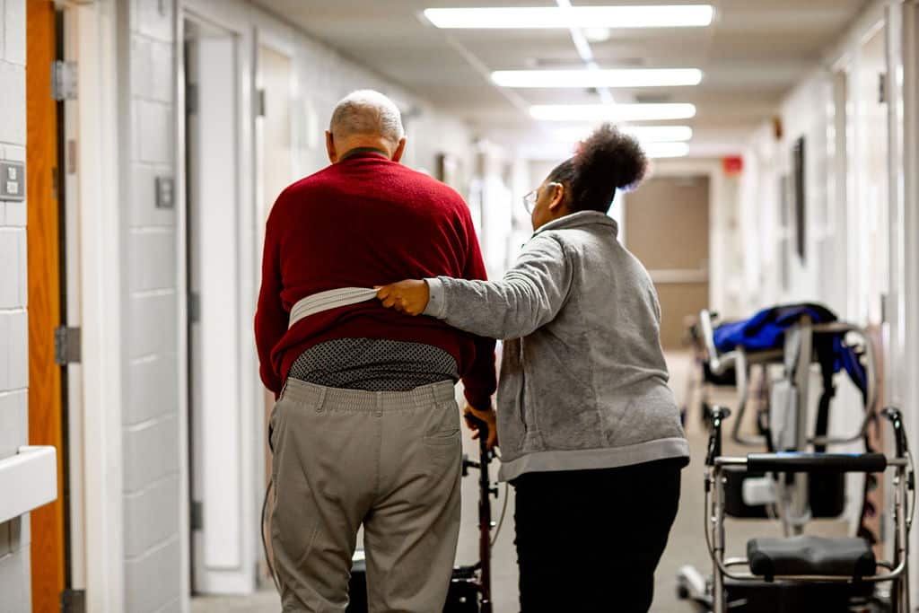 Staff assisting resident in a hallway