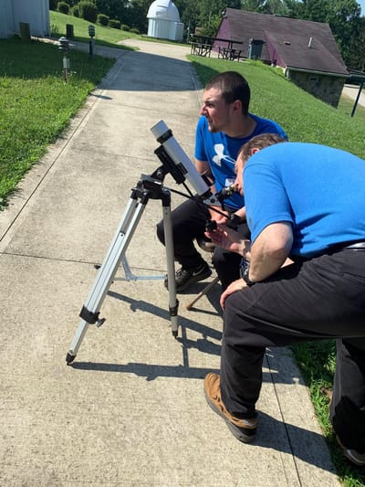 Two individuals using a telescope outside