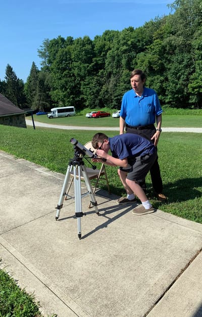 A child using a telescope with an adult nearby