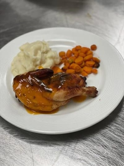 A plated meal with chicken, mashed potatoes, and carrots