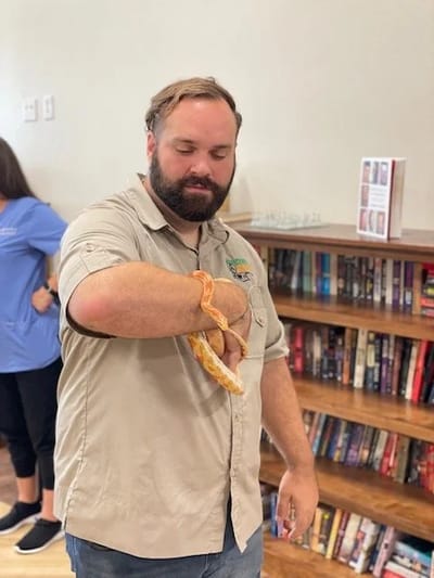 Staff member engaging with a snake in an activity room