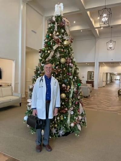 Staff member posing by a decorated Christmas tree in the lobby