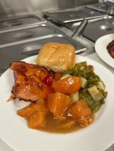 Plate of ham, sweet potatoes, and vegetables served