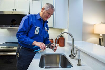 Maintenance staff repairing a sink in the kitchen