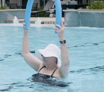 Resident exercising in the pool with water noodles