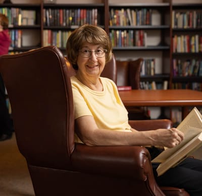 Resident reading in a library area with bookshelves