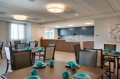 Modern dining room with teal dishware and a kitchen area