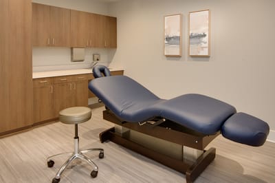 A clean medical examination room with a blue examination table
