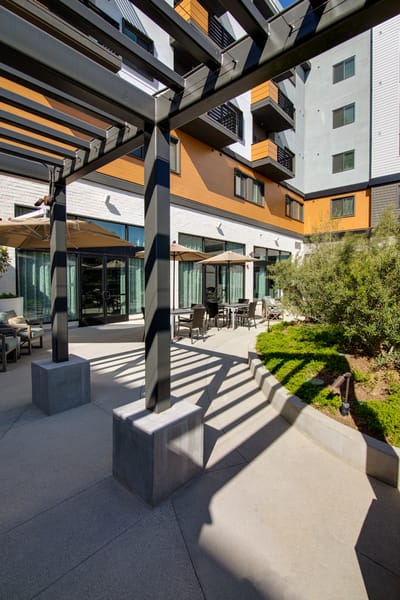 Outdoor seating area with shaded pergola and greenery