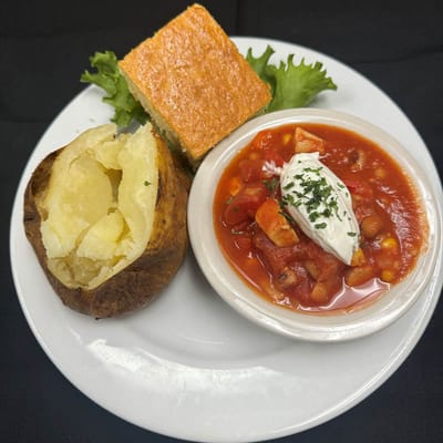 A plate of baked potato, soup, and cornbread