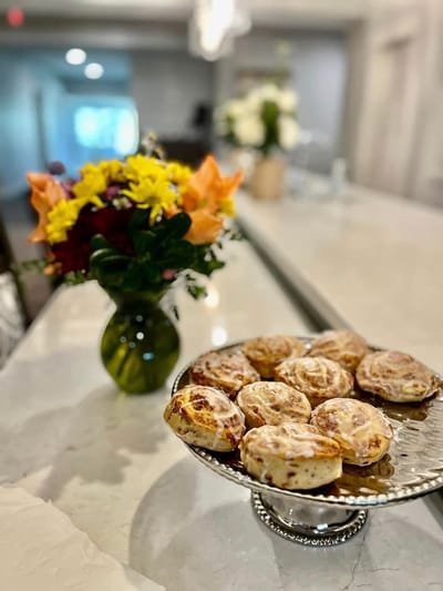 A plate of cinnamon rolls beside a flower vase