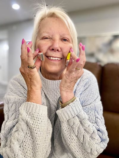 Resident smiling and holding art supplies in a cozy interior