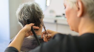 A stylist gives a haircut to a senior resident